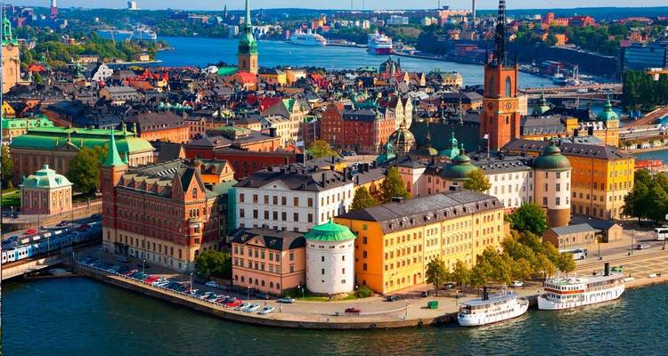 Bright aerial of Stockholm's colourful Gamla Stan peninsula surrounded by sparkling blue water.