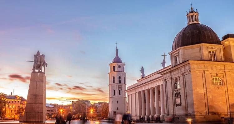 Vilnius Cathedral Square at dusk with bell tower and classical façade under colourful sky.
