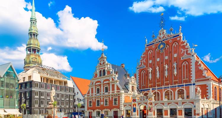 Icónica Casa de las Cabezas Negras y la aguja de San Pedro contra un cielo azul brillante de Riga.
