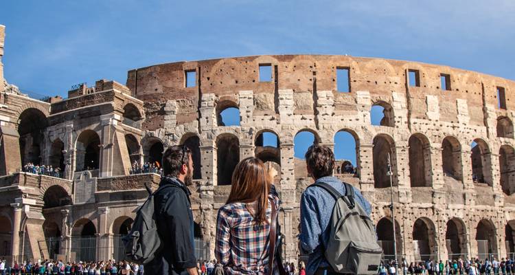 Groupe de voyageurs contemplant les imposantes murailles du Colisée à Rome par une journée ensoleillée.