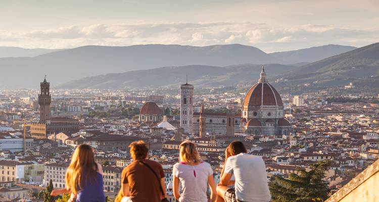 Amis profitant d'une vue panoramique sur le coucher de soleil au-dessus de Florence avec l'emblématique Duomo et le paysage urbain en contrebas.