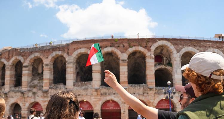 Touriste brandissant un drapeau italien vers l'ancien amphithéâtre romain de Vérone.