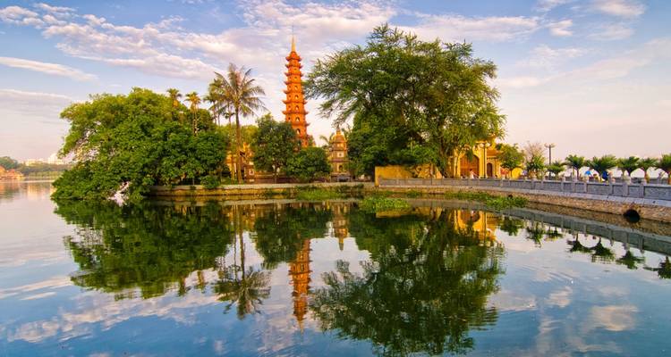 A temple by a lake with trees and a footpath.