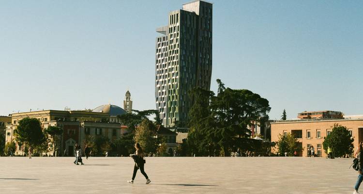 Place urbaine ouverte avec des bâtiments modernes et traditionnels.