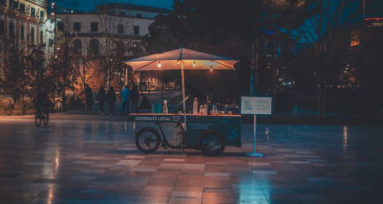 Stand de nourriture avec des lumières sur une place de ville pendant la nuit.