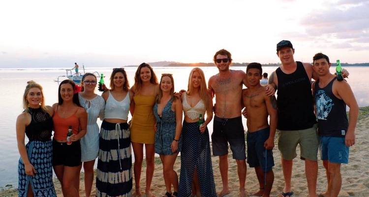 Groep mensen aan het poseren op een strand bij zonsondergang.