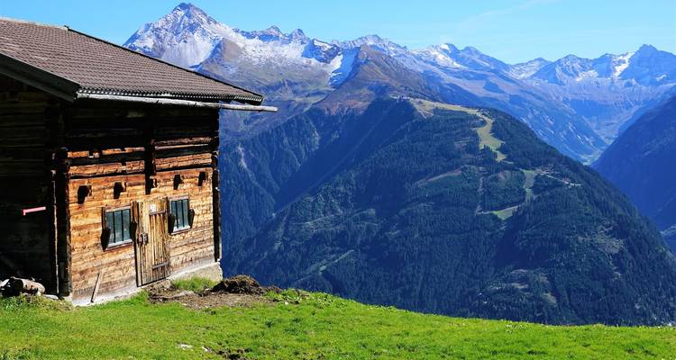 Mountain view with wooden cabin in foreground.