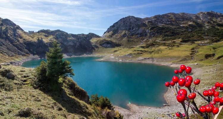 Bergsee mit blauem Wasser und umliegenden Hügeln.