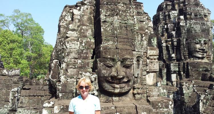 Tourist posiert vor Tempelruinen mit detaillierten Schnitzereien.