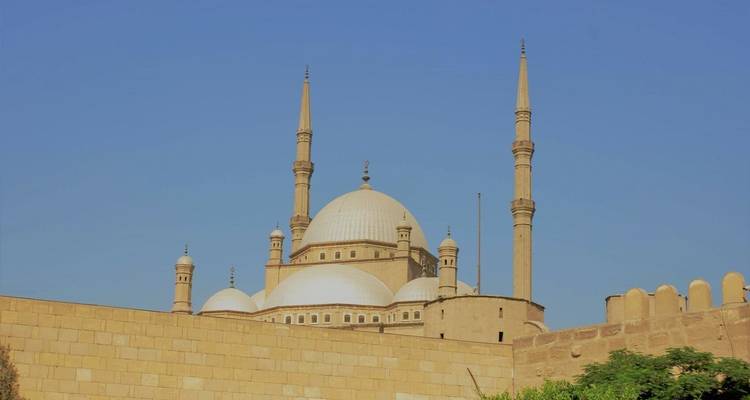 View of a mosque with multiple minarets against a clear sky.