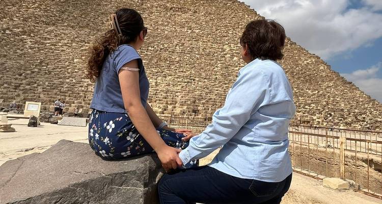 Deux personnes assises regardant la base d'une grande pyramide.