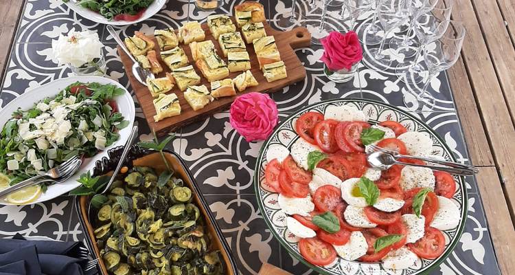 Variedad colorida de ensaladas italianas frescas, mozzarella y verduras asadas dispuestas sobre una mesa con patrones.