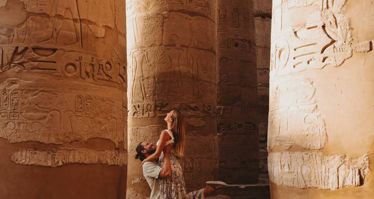 Un couple qui s'enlace près de colonnes antiques couvertes de hiéroglyphes.