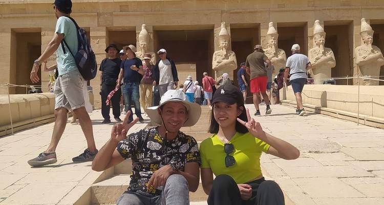 Des touristes posant devant un temple égyptien antique.