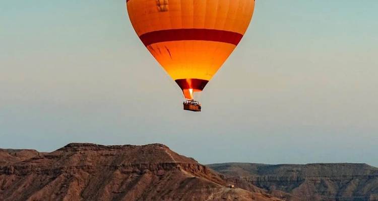 A hot air balloon above desert canyons.