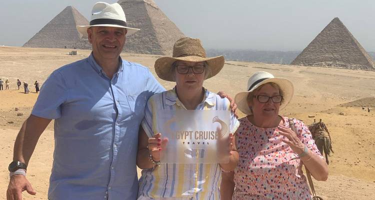 Gruppe von Touristen vor den Pyramiden von Gizeh, die ein Reiseschild halten.