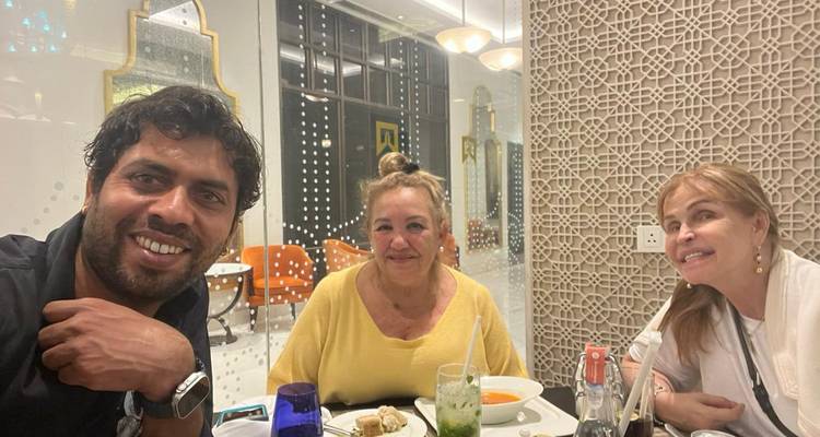 Drie mensen die binnen dineren en glimlachen.