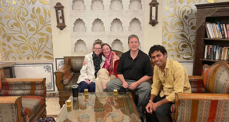 Groepsfoto van vier mensen in een kamer met sierlijke decoratie.