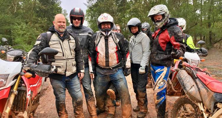 Groupe de motards en terrain boueux.
