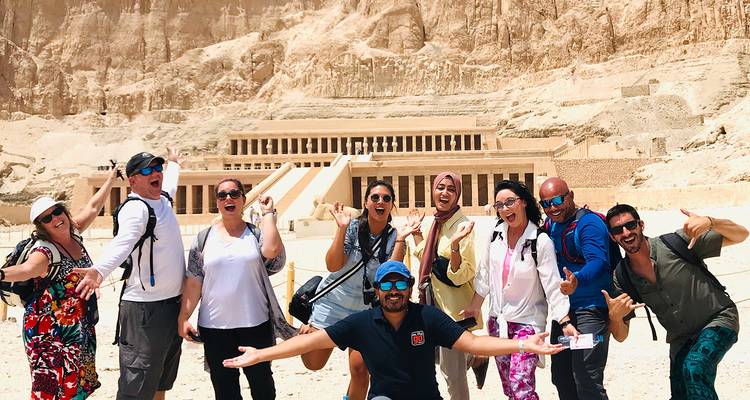 Een groep mensen die vrolijk poseren voor een oude Egyptische tempel.