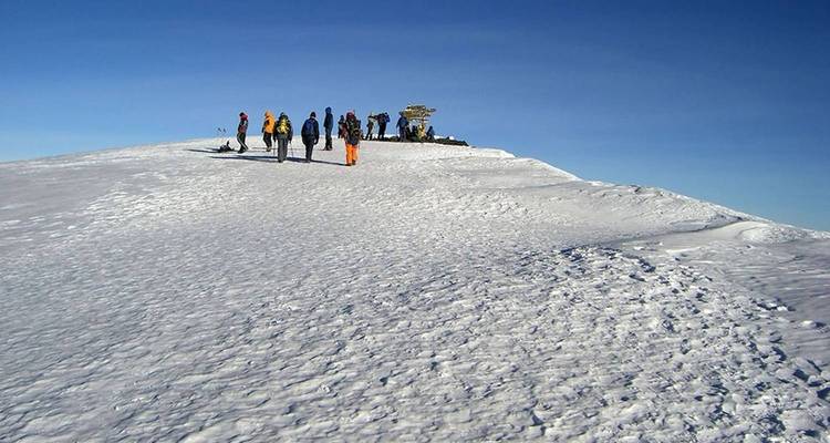 Un groupe de randonneurs marchant sur un sommet enneigé.