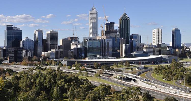 Skyline van een stad met moderne gebouwen en snelwegen op de voorgrond.