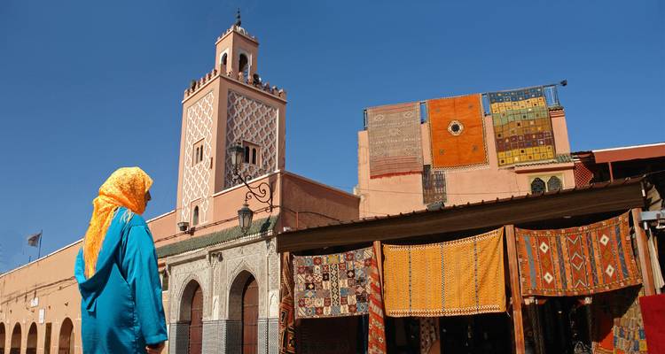 Woman in a blue robe at a vibrant Moroccan market.