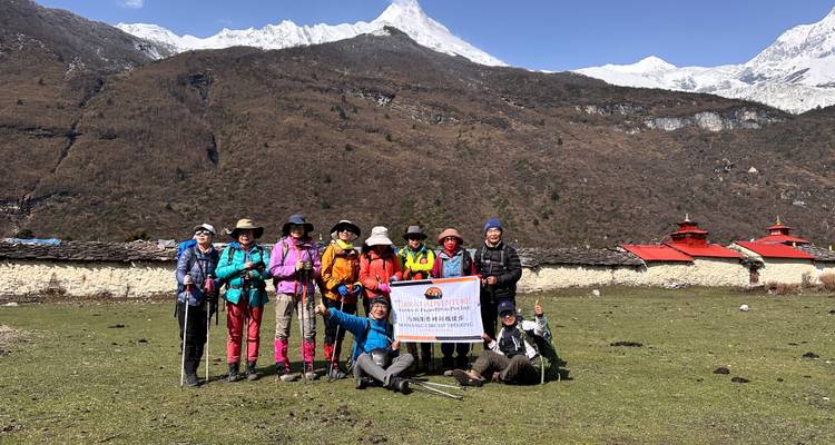 Group of trekkers posing in front of mountains.