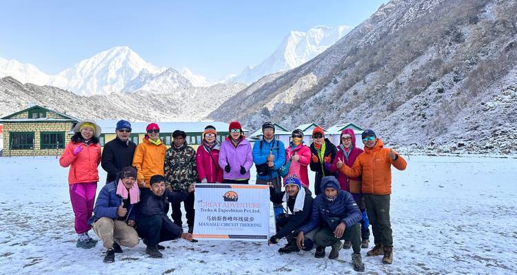 Group of tourists posing in a snowy mountain landscape.