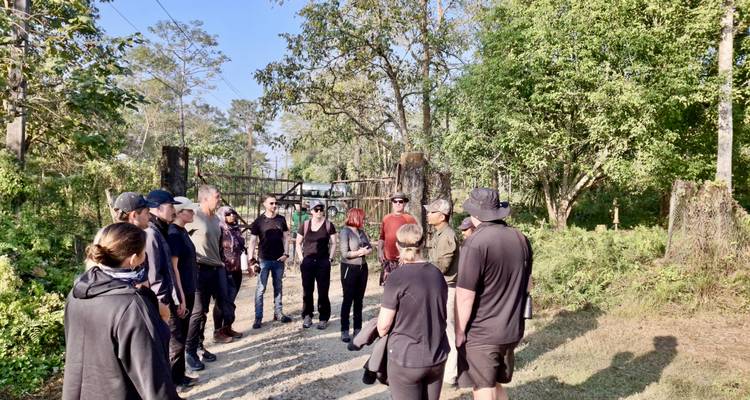 Groupe de personnes debout sur un sentier de terre dans une zone boisée.