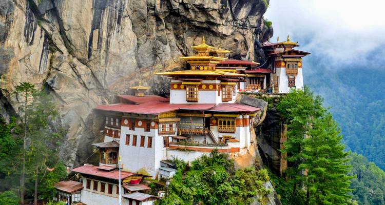 Vue majestueuse d'un monastère à flanc de colline entouré d'une végétation luxuriante.