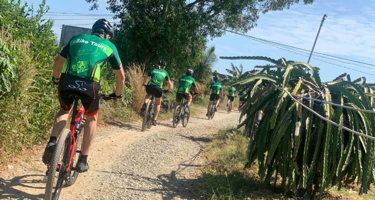 Fietsers op een grindpad met cactusplanten in de buurt.