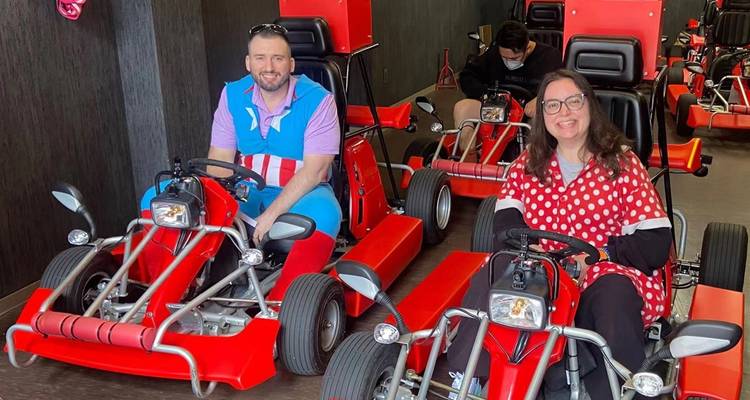 Zwei Personen sitzen in roten Go-Karts in Innenräumen.