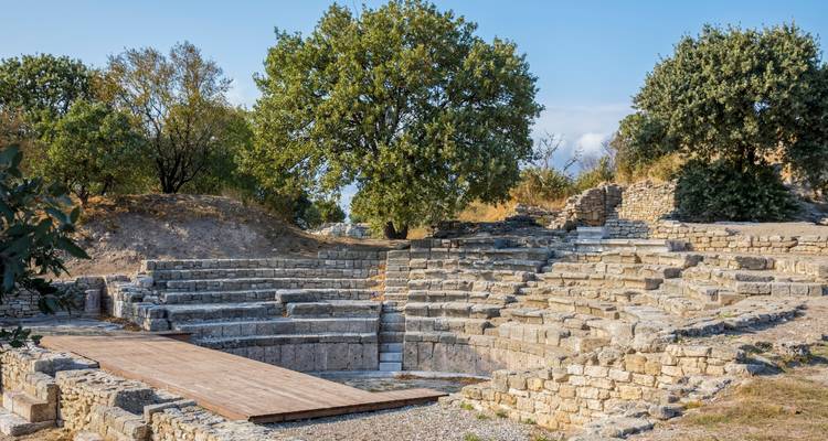 Ruinas de Troya with asientos de piedra y árboles.