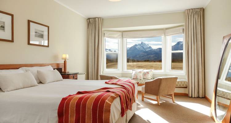 Lichte hotelkamer met erker die een indrukwekkend berglandschap buiten onthult