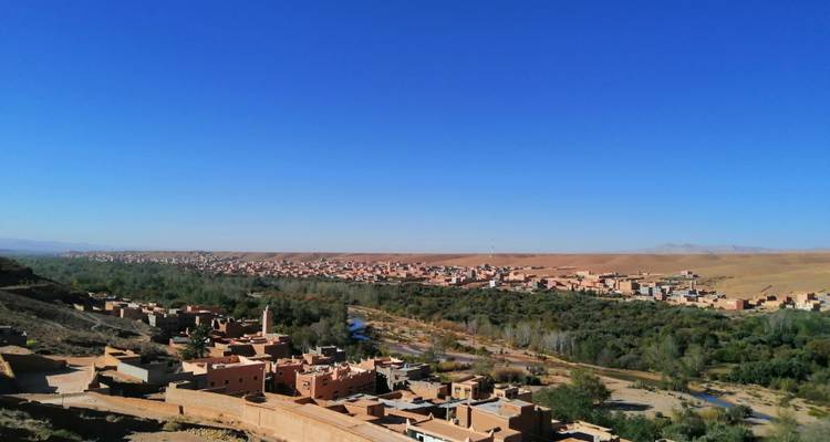 A view over a town with river and desert in the background.