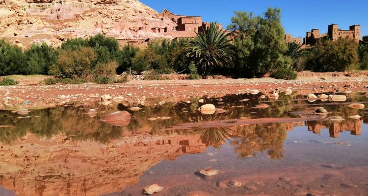 Landscape with reflective water and ancient clay buildings.