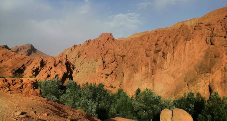 Red rock formations and green trees under a blue sky.