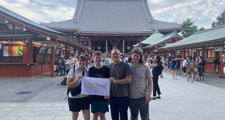 Famille posant avec une bannière de voyage dans la cour d'un temple.