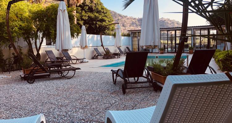 Poolside loungers and parasols with mountain backdrop at a small resort.