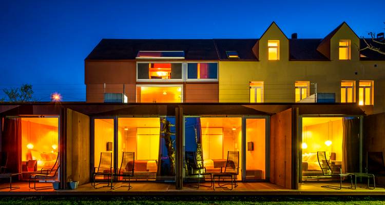 Modern boutique hotel glowing warmly at blue hour with large glass-fronted suites.