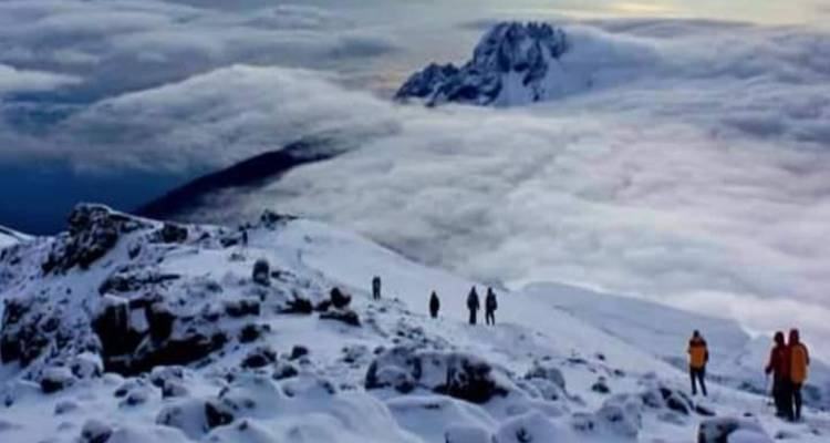 Randonneurs marchant à travers un paysage enneigé dans un cadre montagneux.
