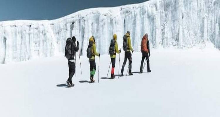 Des randonneurs traversant un paysage enneigé au sommet du Kilimandjaro.