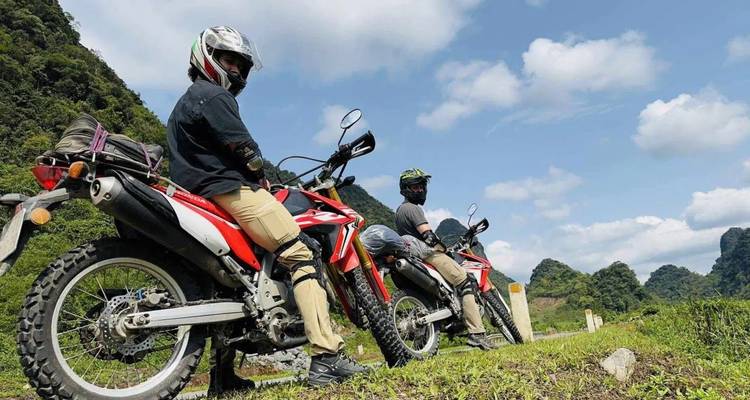 Twee motorrijders die op hun motoren zitten met een bergachtig landschap op de achtergrond.