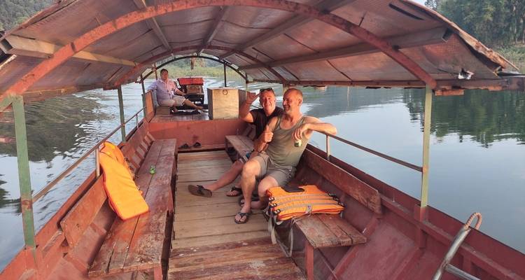 Een groep mensen die in een overdekte boot op een kalme rivier zit.