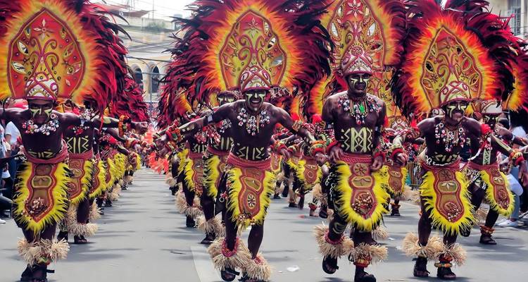 Ein bunter Umzug mit Menschen in traditionellen Kostümen, die auftreten.