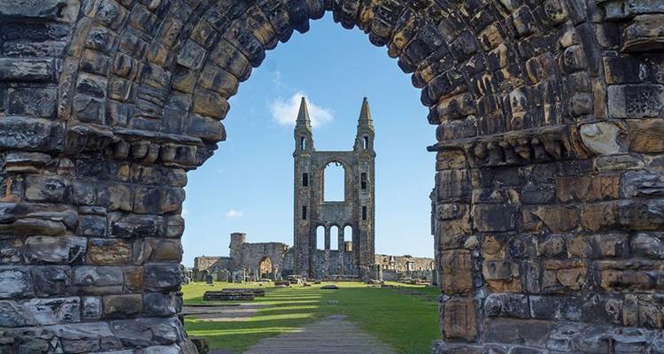 Ruins of a historic stone church seen through an arched window.
