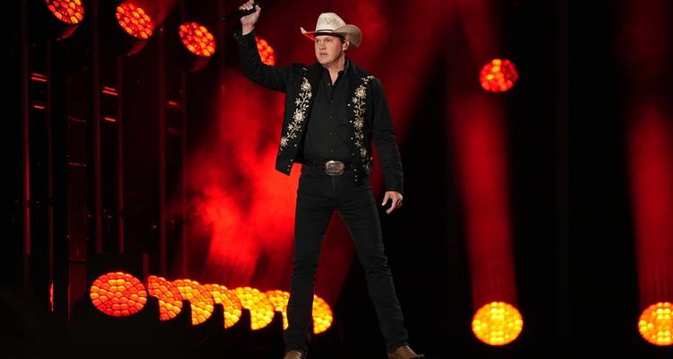 Un artiste solo sur scène avec un arrière-plan éclairé en rouge.