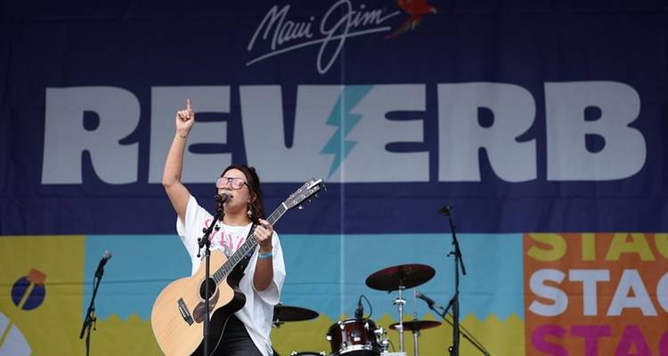 Un chanteur se produisant sur scène avec un décor coloré en arrière-plan.