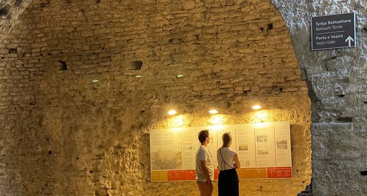 Deux personnes explorant une structure de pierre ancienne avec des panneaux d'information.